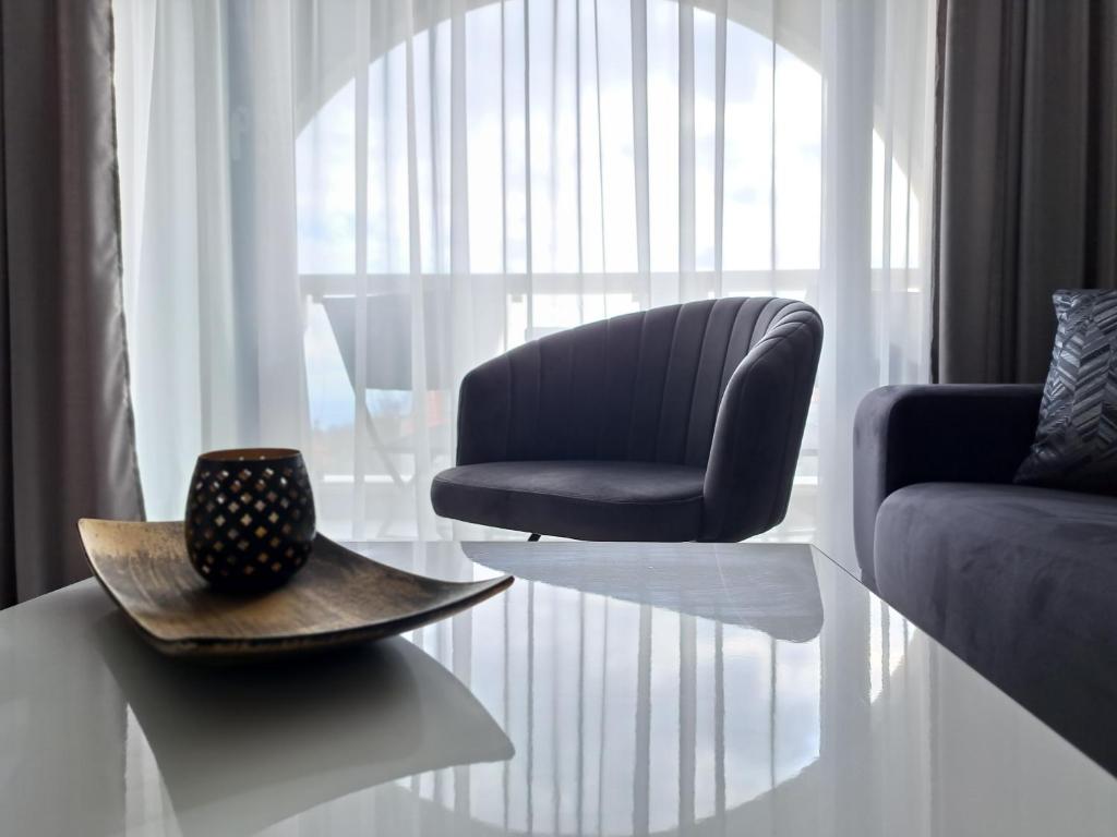 ein Wohnzimmer mit einem Stuhl und einem Tisch in der Unterkunft LUXURY APARTMENT in Mediterranea VARNA Complex, sea view and Infinity pool in Warna