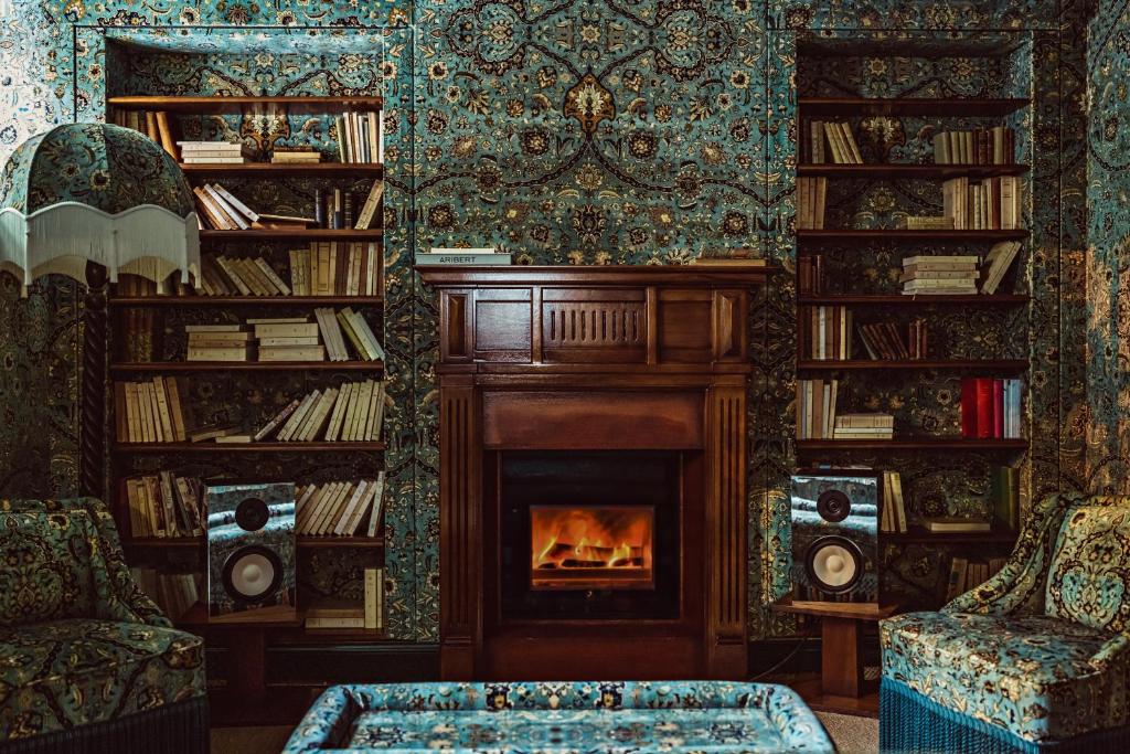 a living room with a fireplace and bookshelves at Hôtel Eldorado Paris in Paris