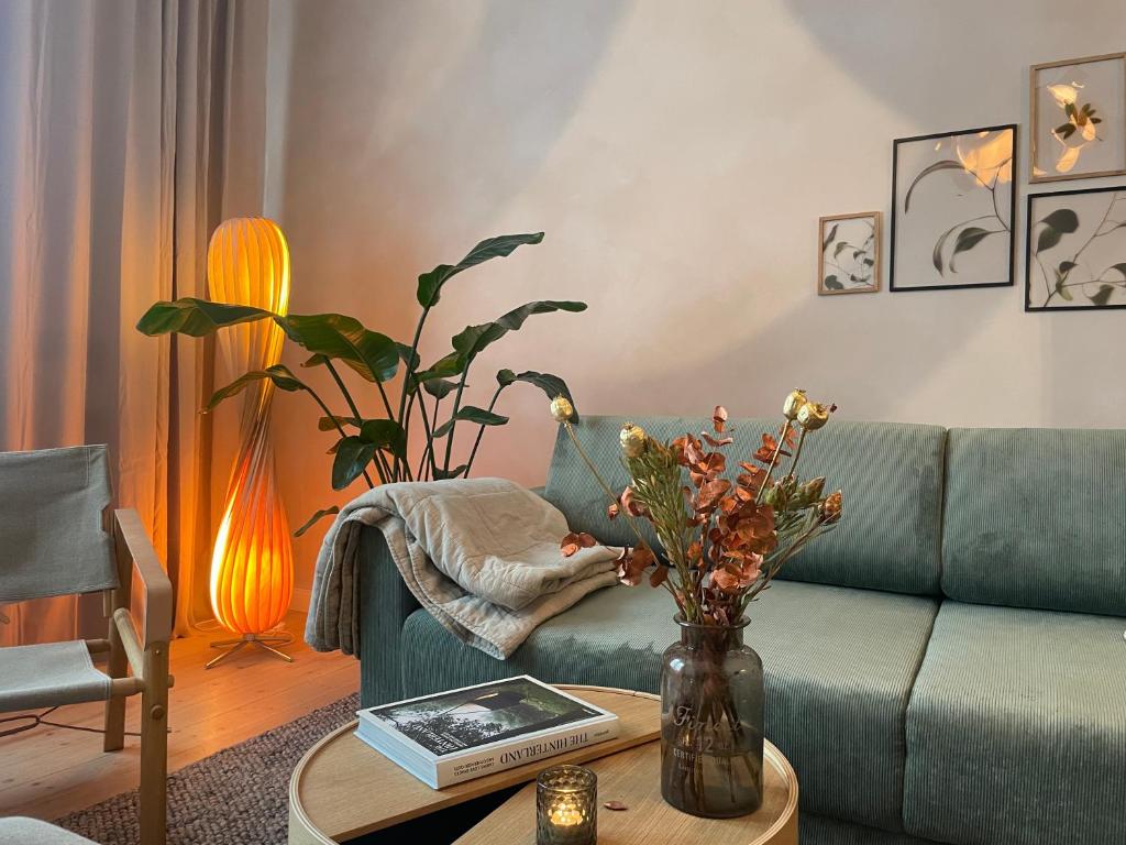 a living room with a couch and a table with flowers at Hygge-Apartment Jena in Jena
