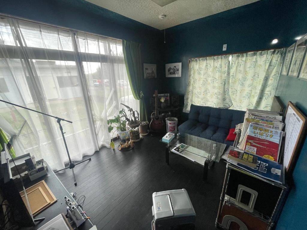 sala de estar con sofá azul y ventanas en Jiji-Baba house, en Noda