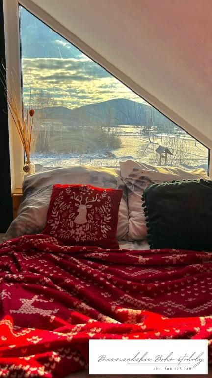 a bed in front of a large window at Bieszczadzkie BOHO stodoły z jacuzzi i sauna na wyłączność in Myczkowce