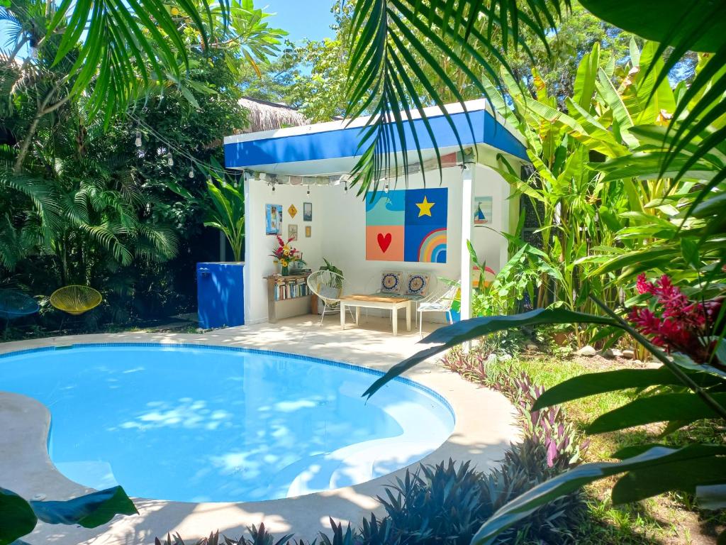 a swimming pool in a garden with a small house at Calma Apartments Costa Rica in Mal País