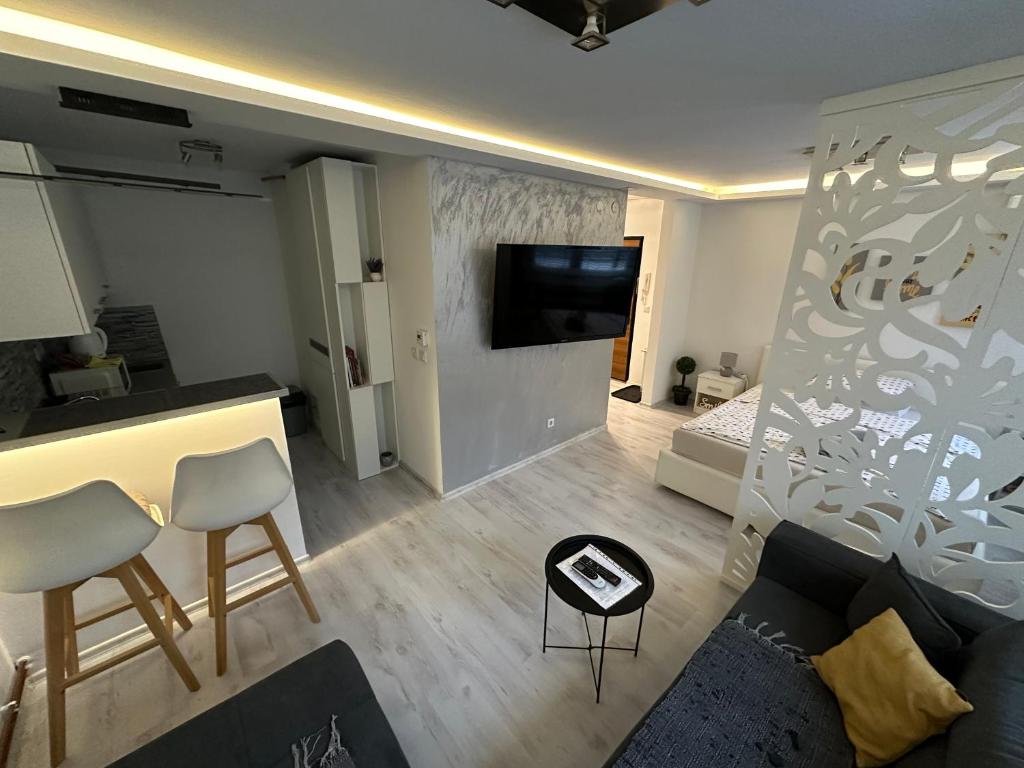 een woonkamer met een bank en een tv aan de muur bij GreyLux Heart of OldTown Sarajevo in Sarajevo