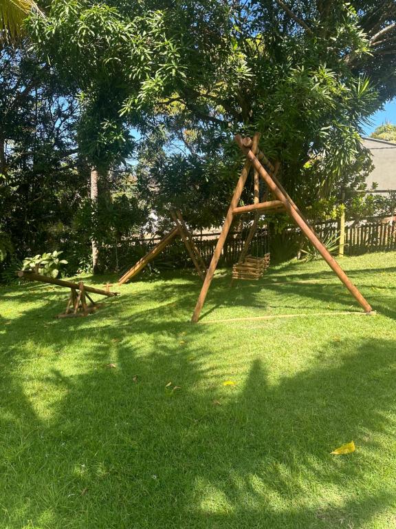 a wooden swing set in the grass in a yard at Pousada Lagoa da Mata in Guarapari