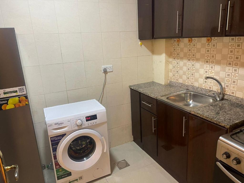 a small kitchen with a washing machine and a sink at Studio R6 in Abu Dhabi