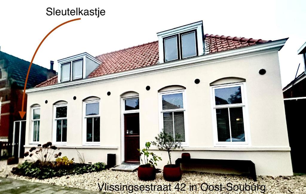 uma casa branca com um telhado vermelho em Sfeervol vakantiehuisje 5 km van het strand em Oost-Souburg