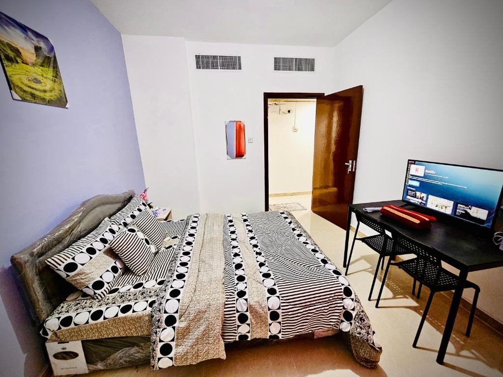 1 dormitorio con 1 cama y escritorio con ordenador en BAITH AL JANNAH LLC Vacation home Rentals, en Abu Dabi