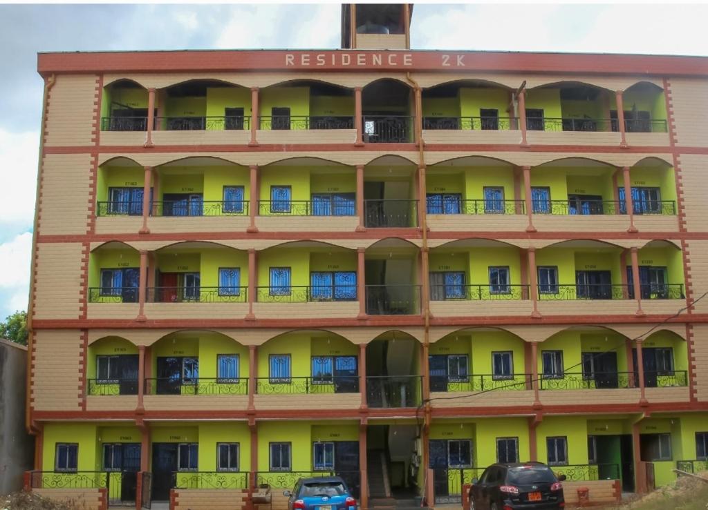 un edificio con balcones y coches aparcados delante en RÉSIDENCE 2k, en Yaoundé