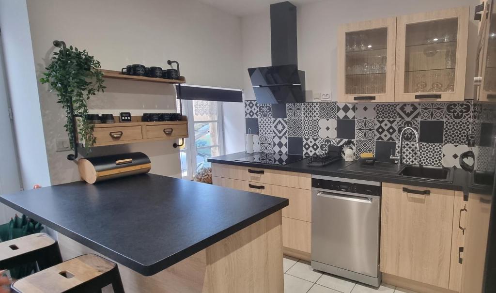 eine Küche mit einer schwarzen Arbeitsplatte und Holzschränken in der Unterkunft La maison Saint-Gervais in Falaise