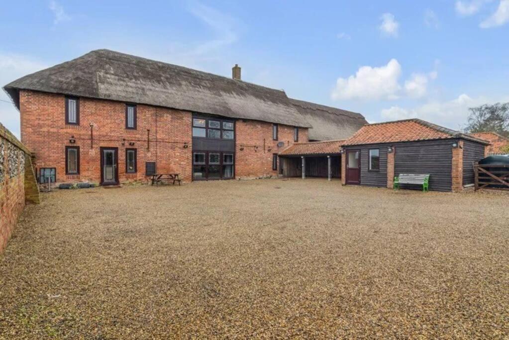 an old brick building with a large yard at amazing barn conversion with hot tub in North Walsham