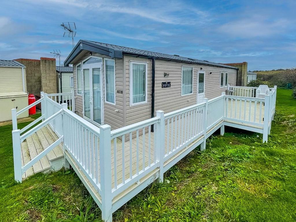 a mobile home with a porch and a white railing at Beautiful Caravan With Decking At Naze Marine Park, Sleeps 8 Ref 17341br in Walton-on-the-Naze