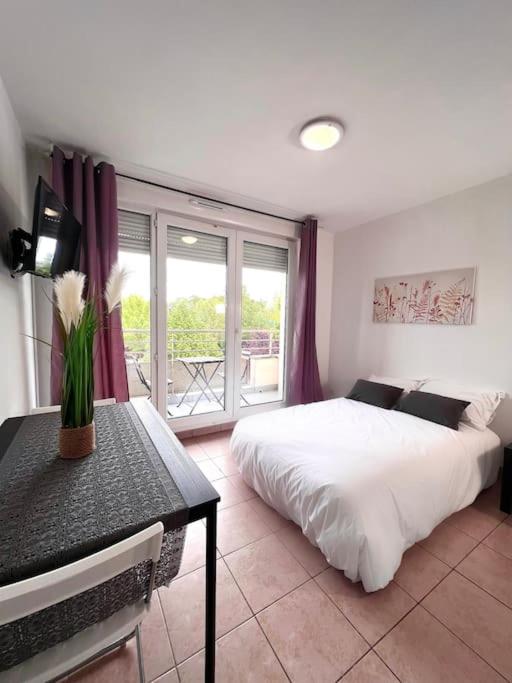 Schlafzimmer mit einem Bett, einem Tisch und einem Fenster in der Unterkunft Appartement DisneyLand Paris Parking et wifi in Montévrain