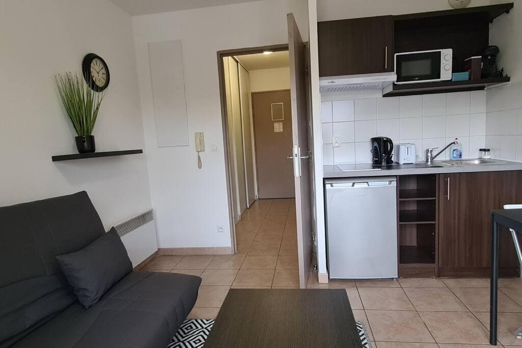 ein Wohnzimmer mit einem Sofa und einer Küche in der Unterkunft Appartement DisneyLand Paris Parking et wifi in Montévrain