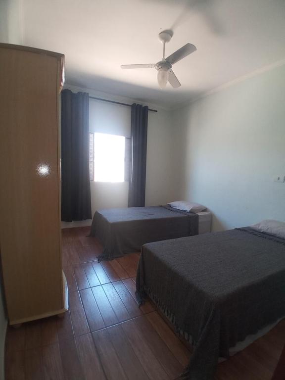 1 Schlafzimmer mit 2 Betten und einem Deckenventilator in der Unterkunft Quarto Aconchego Solteiro in Artur Nogueira
