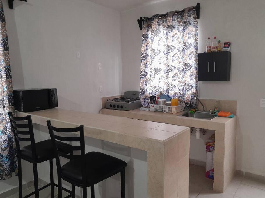 eine Küche mit einer Theke mit 2 Stühlen und einem Tisch in der Unterkunft Casa Privada Palmas 10 con Alberca in Kanasín