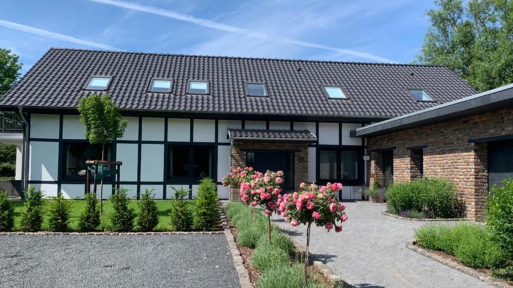 ein Haus mit schwarzem Dach und ein paar Blumen in der Unterkunft Landhaus Bachglück in Zülpich