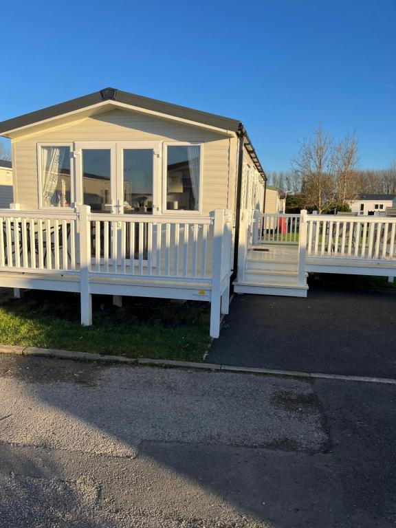a house with a porch and a white fence at Lorraine's Caravan Holiday in Morecambe