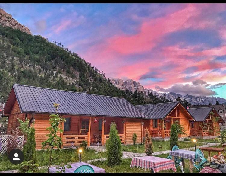 a log cabin in the mountains with a sunset at 2E Villa’s Valbone in Valbonë