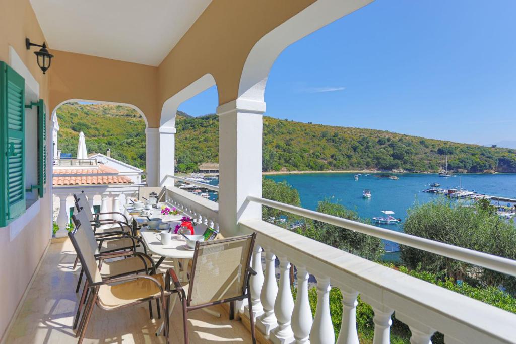 balcón con mesas y sillas y vistas al agua en Evanna House in Saint Stephanos, en Ágios Stéfanos