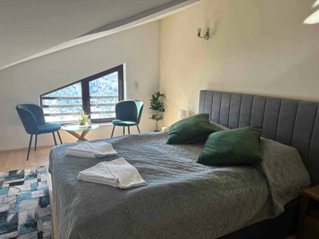 a bedroom with a bed with green pillows and a table at Pamporovo Rhodopi Pearl Apartments - Private Apartments in Pamporovo
