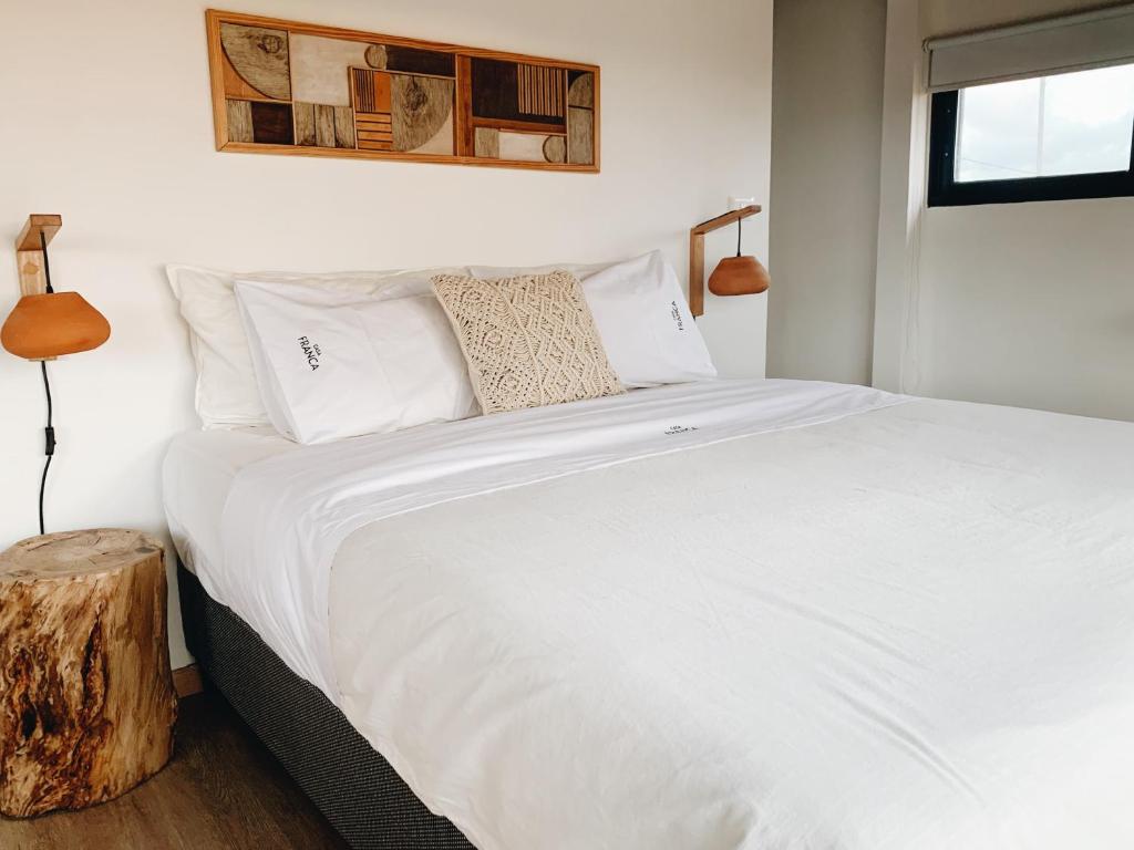 a bedroom with a bed with white sheets and pillows at Casa Franca in José Ignacio