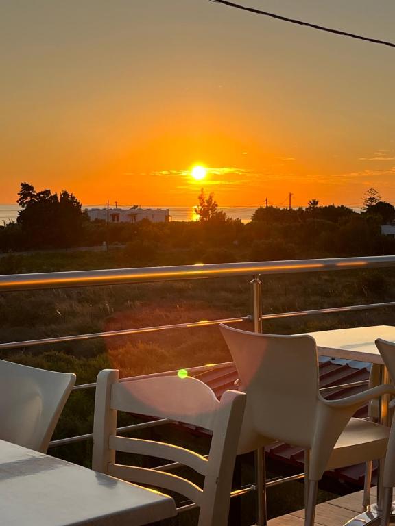 a sunset on a balcony with a table and chairs at Blue Sky in Frangokastello