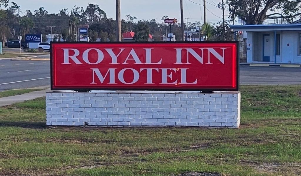 un cartel rojo de motel sentado en el césped en Royal Inn Motel, en Perry