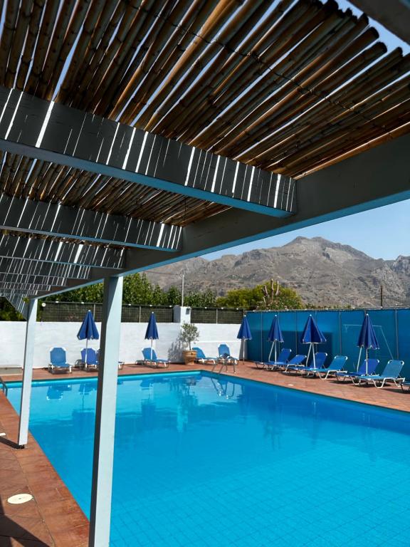 a swimming pool with awning over it with mountains in the background at Blue Sky in Frangokastello