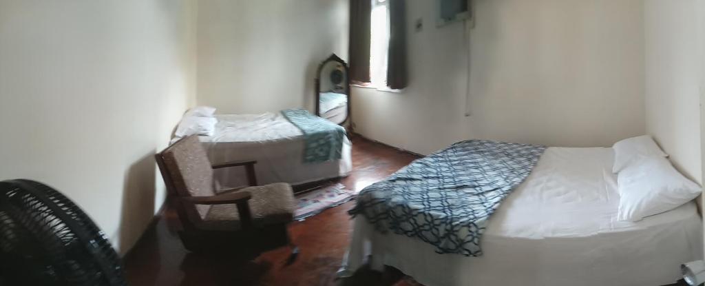 um quarto com uma cama, uma cadeira e uma mesa em Quarto Luxury em Vitória