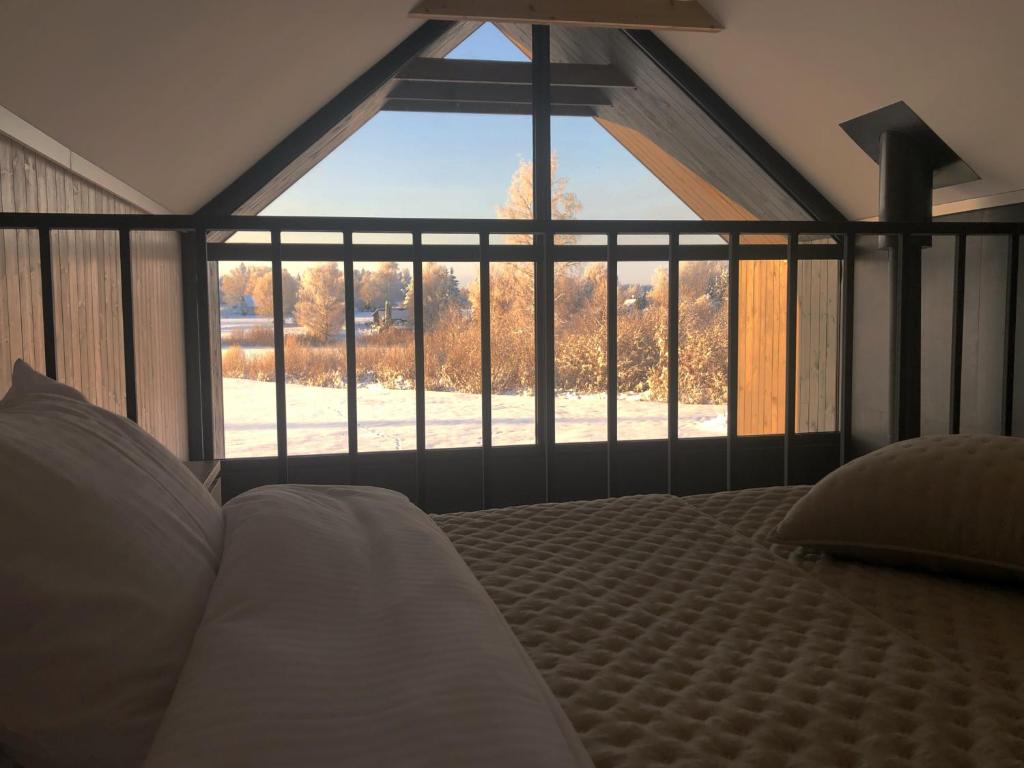 ein Schlafzimmer mit einem Bett und einem großen Fenster in der Unterkunft WakeMālpils brīvdienu mājas in Mālpils
