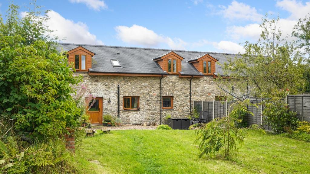 an old stone house with a yard at Mwsogl - Luxurious Family Fishing Lodge Near Aberaeron With Private Fishing in Cross Inn