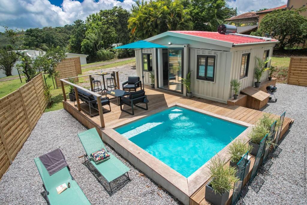 einen Hinterhof mit einem Pool und einem winzigen Haus in der Unterkunft Éco-Chic Bungalow by Bungazur in Saint-Joseph