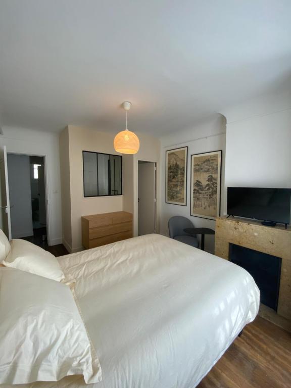um quarto com uma grande cama branca e uma televisão em Maison Auguste em Paris