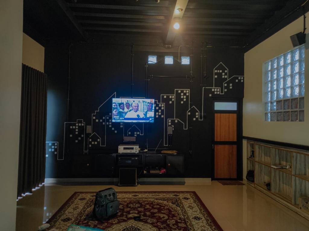 Cette chambre dispose d'une télévision et d'un mur orné de dessins. dans l'établissement Villa Rumah Hijau Syariah, à Cihanjuang 1