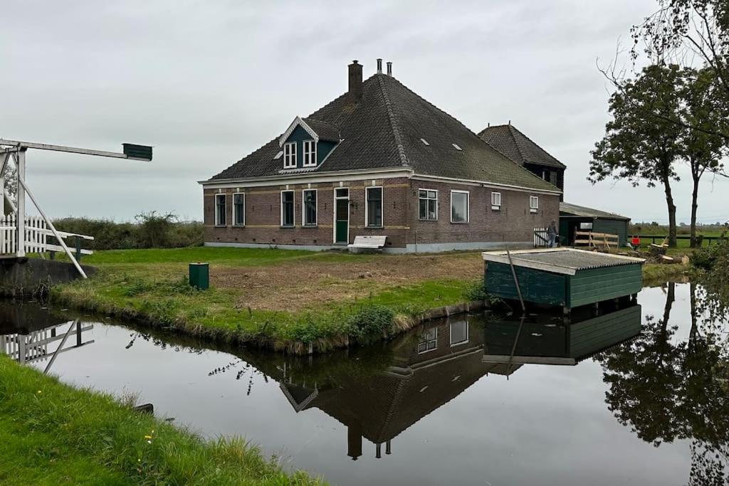 an old house sitting on the side of a river at Beautiful farmhouse near Amsterdam center in Watergang