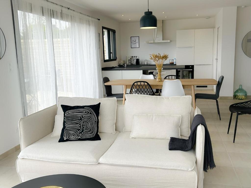un soggiorno con divano bianco e cuscino bianco e nero di Villa Bréhat vue mer et jacuzzi a Tréveneuc