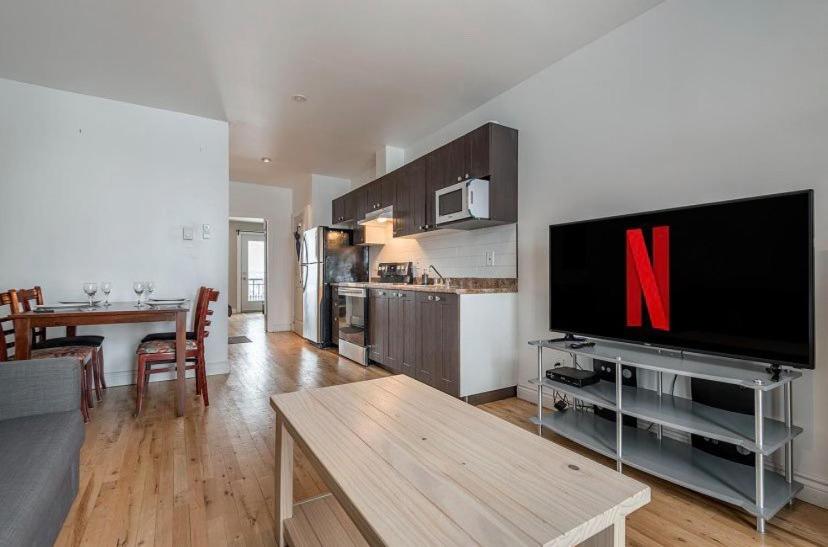 a living room with a large tv and a table at 5-STAR Prime Location - Bright Condo in Montréal