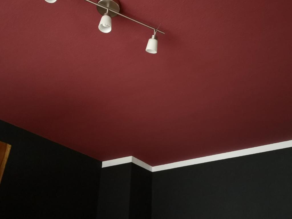 een kamer met een rode muur en een plafond bij THE BLACKTAGON Cozy Apartment in Frankfurt am Main