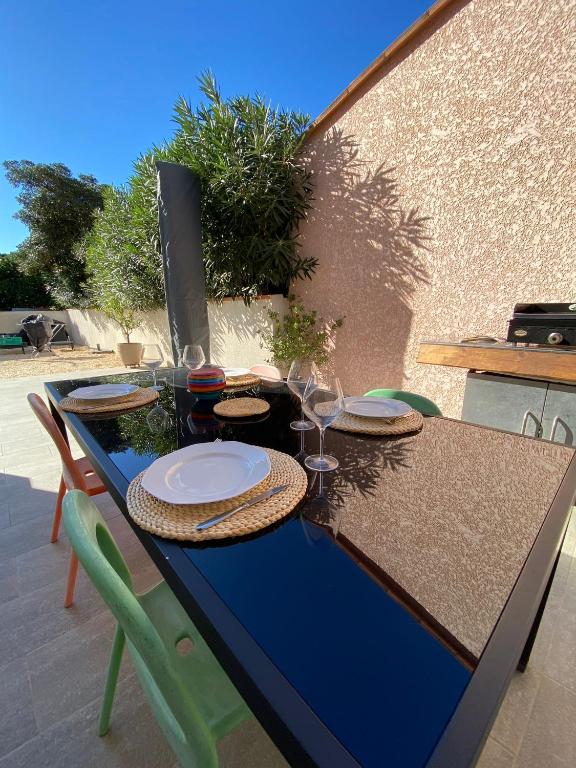 une table bleue avec des assiettes et des verres à vin dans l&#39;établissement VILLA 2 CHAMBRES à STE MARIE LA MER, à Sainte-Marie-la-Mer