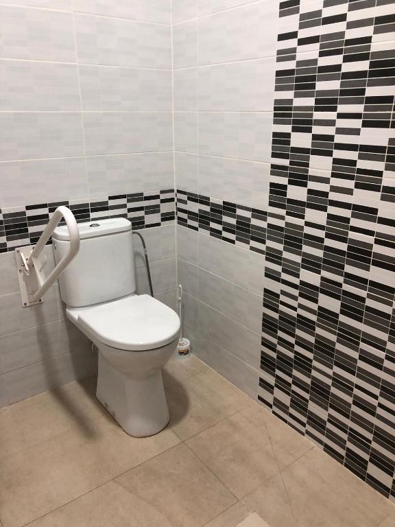 a bathroom with a toilet with a black and white tiled wall at Hotel Kasa in Las Palmas de Gran Canaria