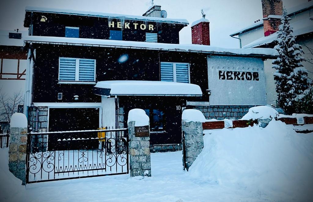 een huis bedekt met sneeuw met een hek bij Willa Hektor in Szklarska Poręba