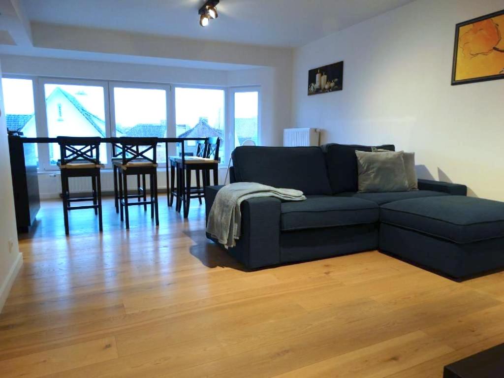 a living room with a blue couch and a table at Appartement Ter Duinen - Lux Living in De Panne