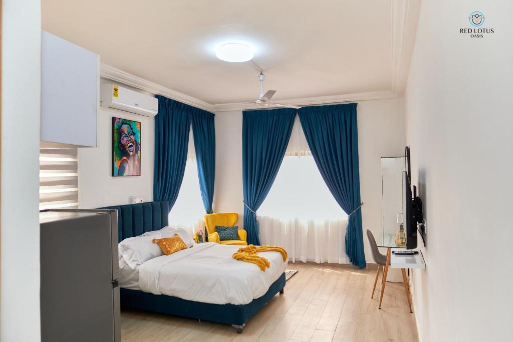 een slaapkamer met een bed met blauwe gordijnen en een televisie bij Charming Rooftop Apartments with Great view & Free Strong Wi-Fi - 40percent Long-stay Disc- Red Lotus Oasis in Accra