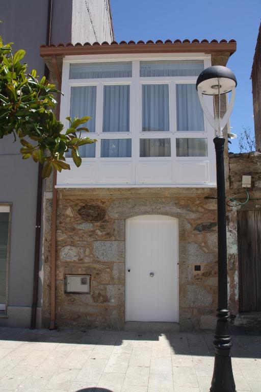 un edificio con una puerta blanca y una luz de la calle en Casa de Ángeles, en Finisterre