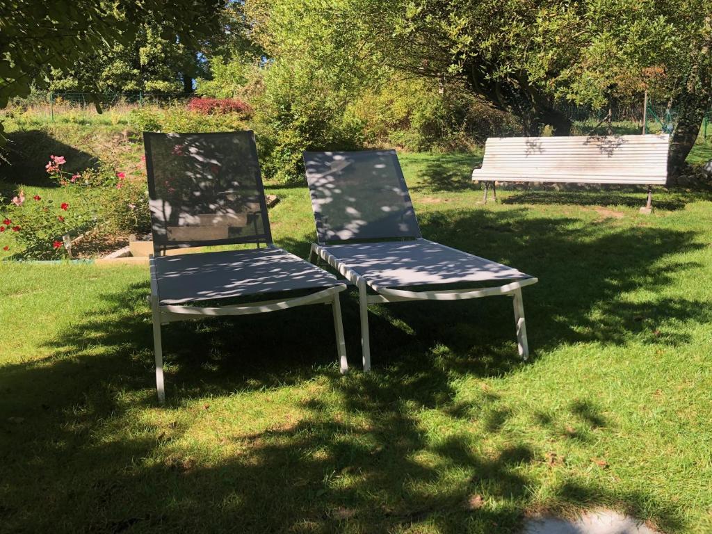 due sedie sedute vicino a una panchina nell'erba di L'Entre 2 - Suite de charme avec sauna et baignoire balnéo a Amay