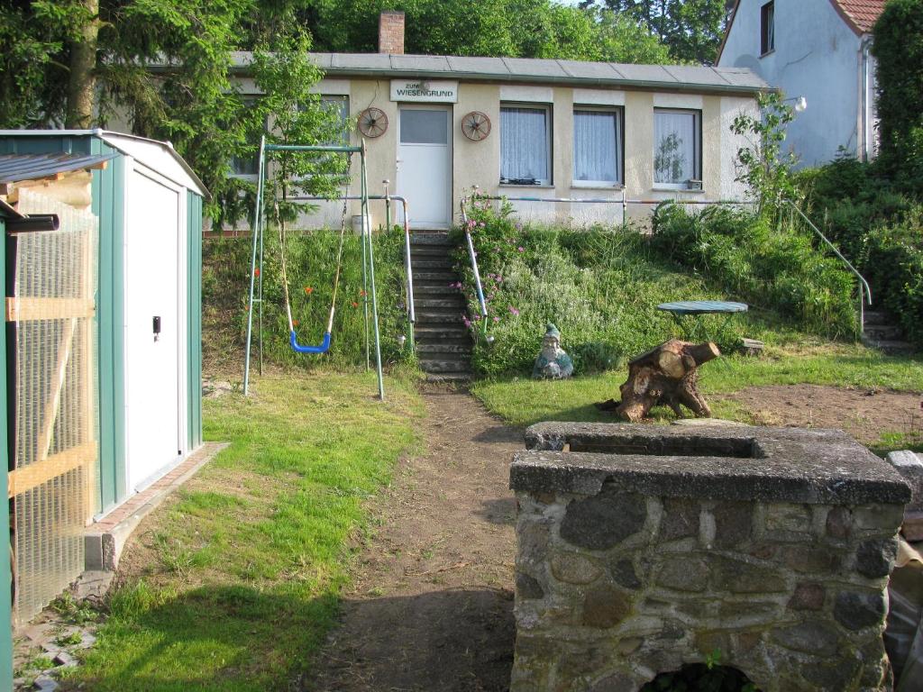 a dog sitting on a stone wall in front of a house at Bungalow in Altglietzen für 2 Personen und 1 Kind bis 6 Jahren in Altglietzen