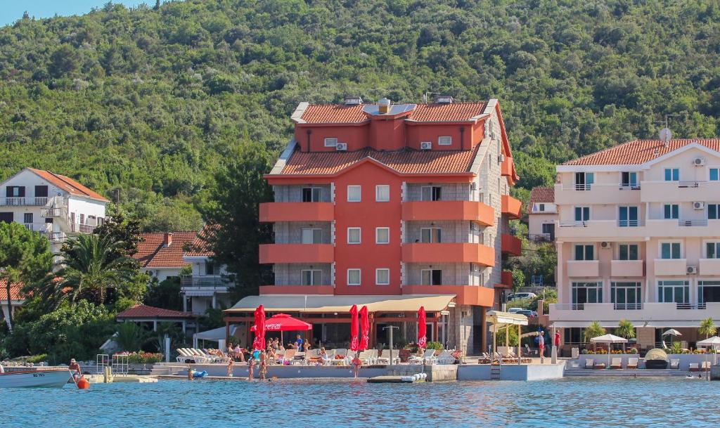 un gran edificio rojo en la orilla de un cuerpo de agua en Apart hotel Samardzic en Tivat