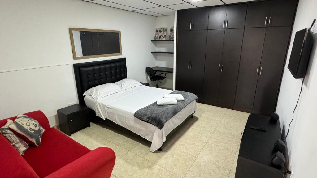 um quarto com uma cama e um sofá vermelho em Acogedor apartaestudio ubicado en la zona rosa de Pereira em Pereira