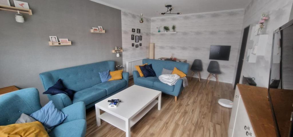 a living room with blue couches and a white table at Friesenhaus1822 in Tettens in Wangerland