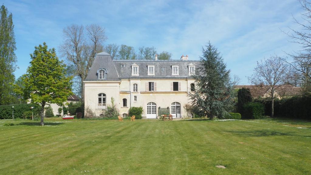 Manoir 19e vallée Chevreuse, idéal JO Paris 2024 في Le Mesnil-Saint-Denis: منزل كبير مع ساحة عشبية كبيرة